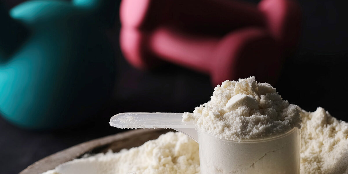 Scoop of creatine powder and gym weights