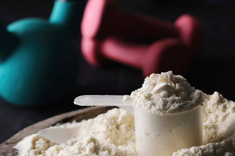 Scoop of creatine powder and gym weights